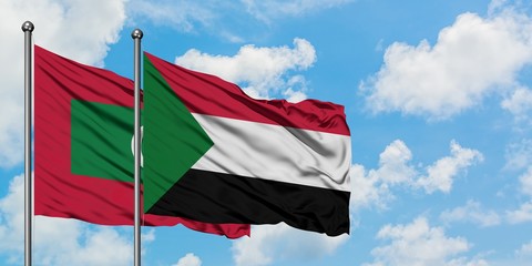 Maldives and Sudan flag waving in the wind against white cloudy blue sky together. Diplomacy concept, international relations.