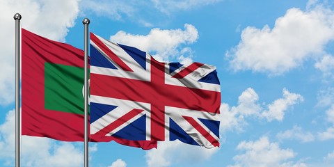 Maldives and United Kingdom flag waving in the wind against white cloudy blue sky together. Diplomacy concept, international relations.