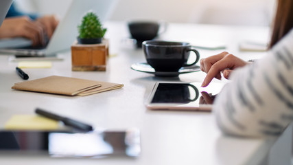 Fototapeta na wymiar A woman using and pointing finger at a tablet pc with coffee cup on the table