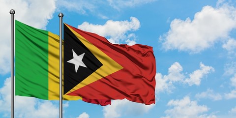 Mali and East Timor flag waving in the wind against white cloudy blue sky together. Diplomacy concept, international relations.