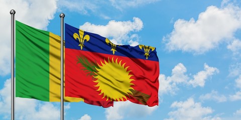 Mali and Guadeloupe flag waving in the wind against white cloudy blue sky together. Diplomacy concept, international relations.