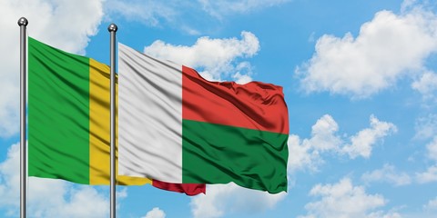 Mali and Madagascar flag waving in the wind against white cloudy blue sky together. Diplomacy concept, international relations.
