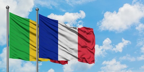 Mali and Reunion flag waving in the wind against white cloudy blue sky together. Diplomacy concept, international relations.