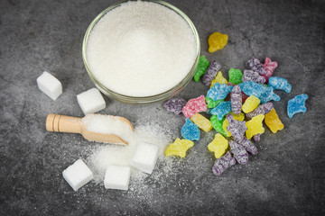 Fototapeta na wymiar White sugar and colorful candy sweet on the dark table background / No sugar in diet causes obesity diabetes and other health problems concept