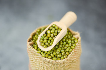 Green mung beans in the sack with wooden scoop - Mung bean seed cereal whole grains