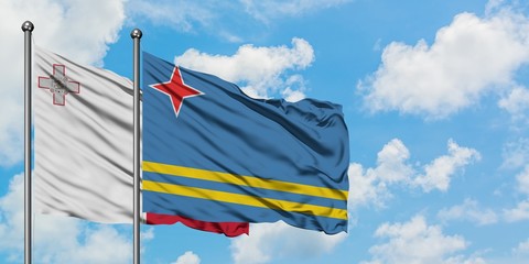 Malta and Aruba flag waving in the wind against white cloudy blue sky together. Diplomacy concept, international relations.