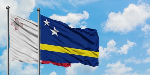 Malta and Curacao flag waving in the wind against white cloudy blue sky together. Diplomacy concept, international relations.
