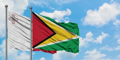 Malta and Guyana flag waving in the wind against white cloudy blue sky together. Diplomacy concept, international relations.