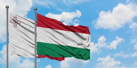 Malta and Hungary flag waving in the wind against white cloudy blue sky together. Diplomacy concept, international relations.