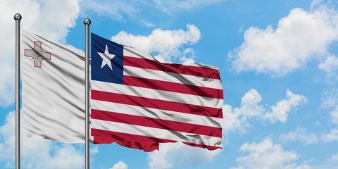 Malta and Liberia flag waving in the wind against white cloudy blue sky together. Diplomacy concept, international relations.