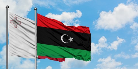 Malta and Libya flag waving in the wind against white cloudy blue sky together. Diplomacy concept, international relations.
