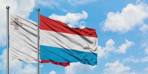 Malta and Luxembourg flag waving in the wind against white cloudy blue sky together. Diplomacy concept, international relations.