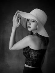 Portrait of Asian woman wearing dress and hat, black and white filter.