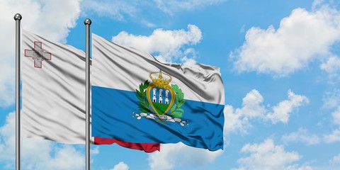 Malta and San Marino flag waving in the wind against white cloudy blue sky together. Diplomacy concept, international relations.