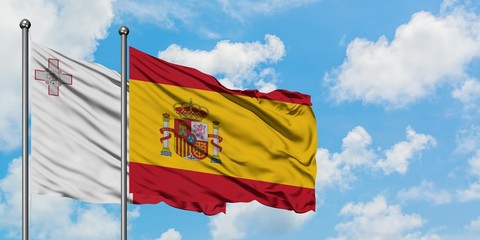 Malta and Spain flag waving in the wind against white cloudy blue sky together. Diplomacy concept, international relations.