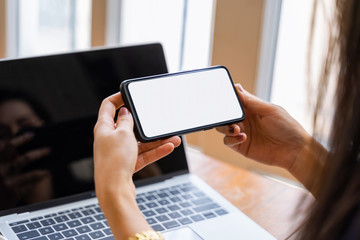 Cropped shot view of female hands holding smart phone in horizontal position with blank screen for your text message or information content.