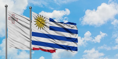 Malta and Uruguay flag waving in the wind against white cloudy blue sky together. Diplomacy concept, international relations.