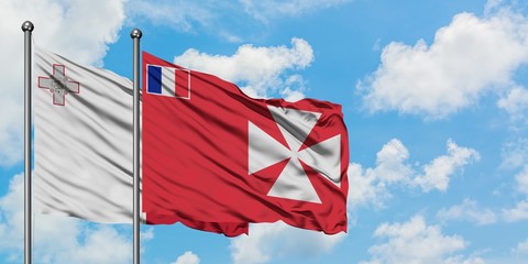 Malta and Wallis And Futuna flag waving in the wind against white cloudy blue sky together. Diplomacy concept, international relations.