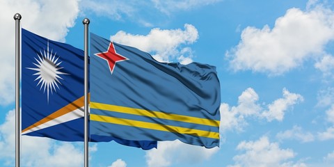 Marshall Islands and Aruba flag waving in the wind against white cloudy blue sky together. Diplomacy concept, international relations.