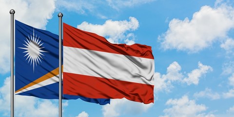 Marshall Islands and Austria flag waving in the wind against white cloudy blue sky together. Diplomacy concept, international relations.