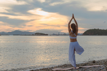 Young woman is practicing yoga at mountain lake