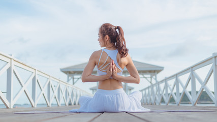 Young women doing yoga, outdoor exercise in the beautiful white bridge The morning sunrise, Namaste...