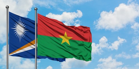 Marshall Islands and Burkina Faso flag waving in the wind against white cloudy blue sky together. Diplomacy concept, international relations.