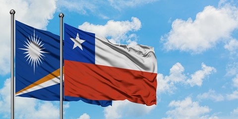 Marshall Islands and Chile flag waving in the wind against white cloudy blue sky together....