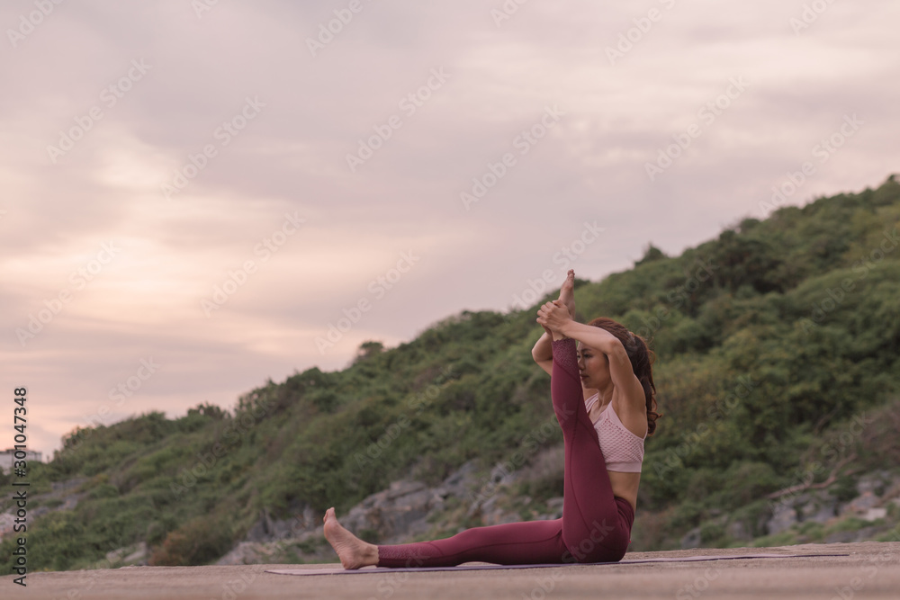 Wall mural young women practicing yoga and practicing yoga postures amazing yoga landscape in the beautiful sky