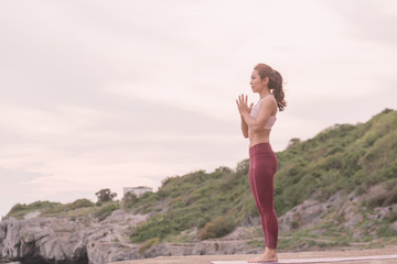 Young women doing yoga, practicing yoga postures on the mountain range Yoga landscape Beautiful sky and enjoying the sea view On the concept of exercise, health care