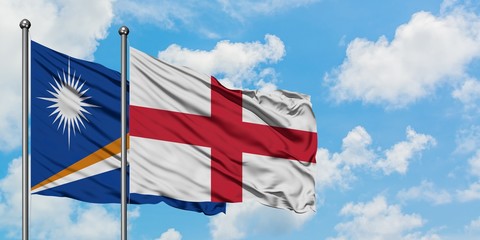 Marshall Islands and England flag waving in the wind against white cloudy blue sky together. Diplomacy concept, international relations.