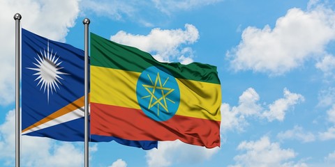 Marshall Islands and Ethiopia flag waving in the wind against white cloudy blue sky together....