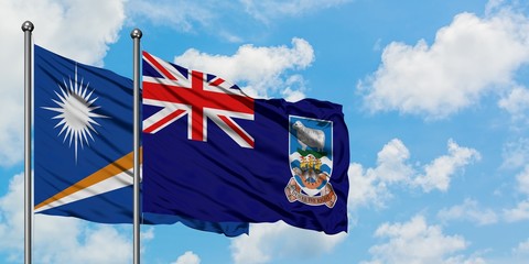 Marshall Islands and Falkland Islands flag waving in the wind against white cloudy blue sky together. Diplomacy concept, international relations.