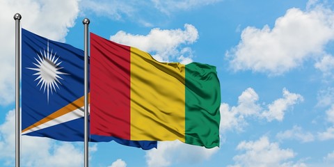 Marshall Islands and Guinea flag waving in the wind against white cloudy blue sky together. Diplomacy concept, international relations.