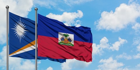 Marshall Islands and Haiti flag waving in the wind against white cloudy blue sky together....