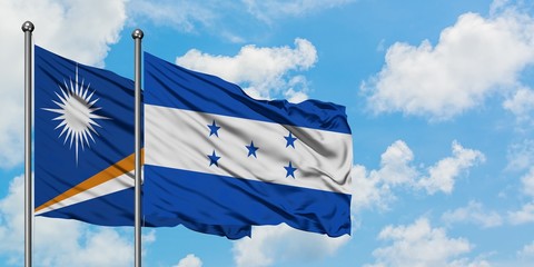 Marshall Islands and Honduras flag waving in the wind against white cloudy blue sky together. Diplomacy concept, international relations.