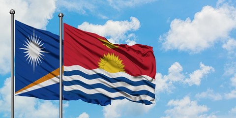 Marshall Islands and Kiribati flag waving in the wind against white cloudy blue sky together. Diplomacy concept, international relations.