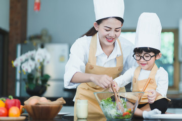 Happy family. Asian mother and son in the kitchen. The mother and son help make a vegetable salad by teaching children to make healthy salad dishes for dinner.