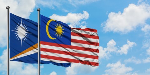 Marshall Islands and Malaysia flag waving in the wind against white cloudy blue sky together. Diplomacy concept, international relations.