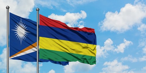 Marshall Islands and Mauritius flag waving in the wind against white cloudy blue sky together. Diplomacy concept, international relations.