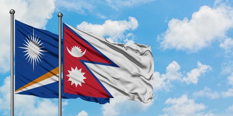 Marshall Islands and Nepal flag waving in the wind against white cloudy blue sky together....