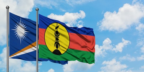 Marshall Islands and New Caledonia flag waving in the wind against white cloudy blue sky together. Diplomacy concept, international relations.