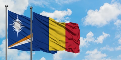 Marshall Islands and Romania flag waving in the wind against white cloudy blue sky together....