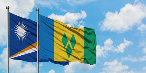 Marshall Islands and Saint Vincent And The Grenadines flag waving in the wind against white cloudy blue sky together. Diplomacy concept, international relations.