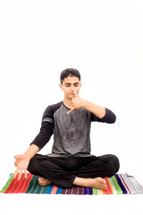 Full body shot of male teenager doing Nadi Shdhana Pranayama or Alternate Nostril Breathing...
