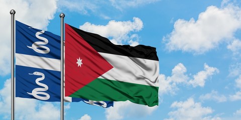Martinique and Jordan flag waving in the wind against white cloudy blue sky together. Diplomacy concept, international relations.