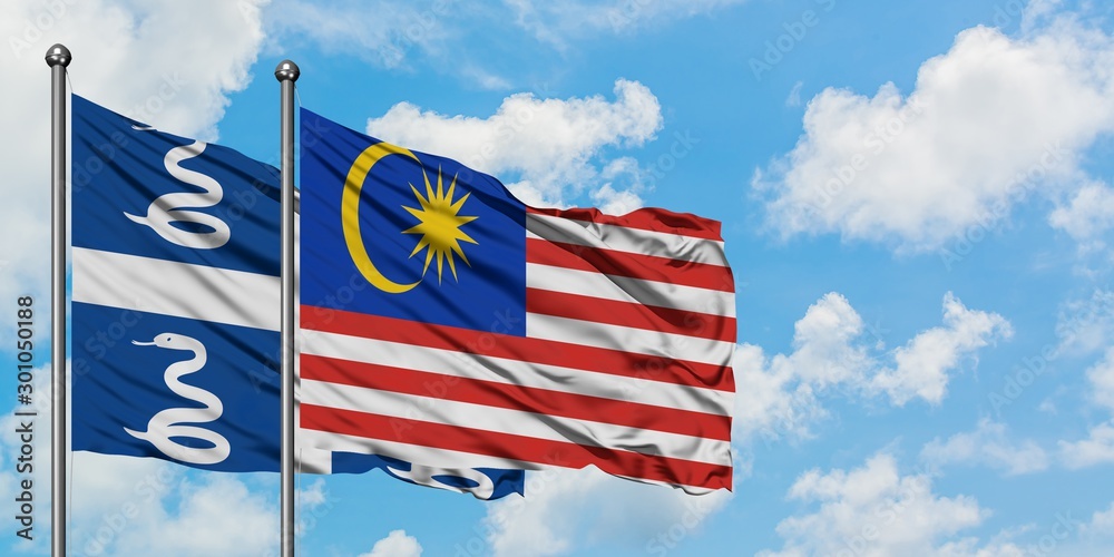 Wall mural Martinique and Malaysia flag waving in the wind against white cloudy blue sky together. Diplomacy concept, international relations.