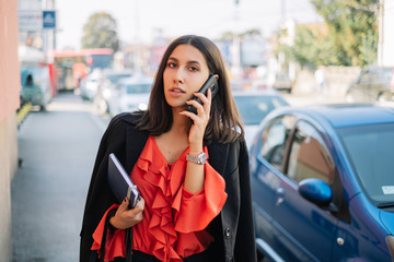 Brunette woman walking on sidewalk while talking on phone
