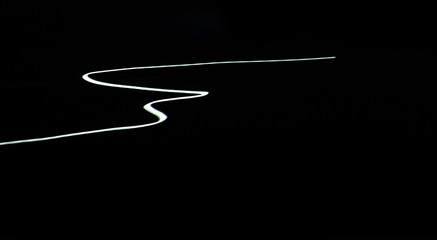 Motion blur car light trails on highway against black background