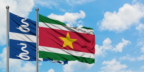 Martinique and Suriname flag waving in the wind against white cloudy blue sky together. Diplomacy concept, international relations.